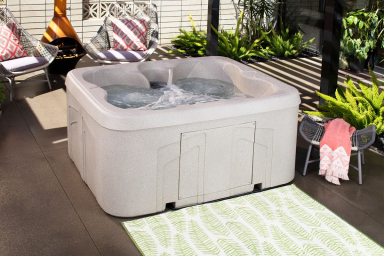 Hot tub on a patio with chairs and plants