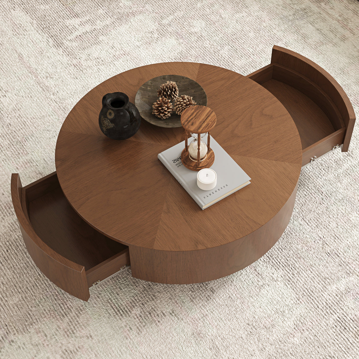 A round wooden coffee table with two pull-out storage drawers, shown on a textured light gray rug with decorative items on top.