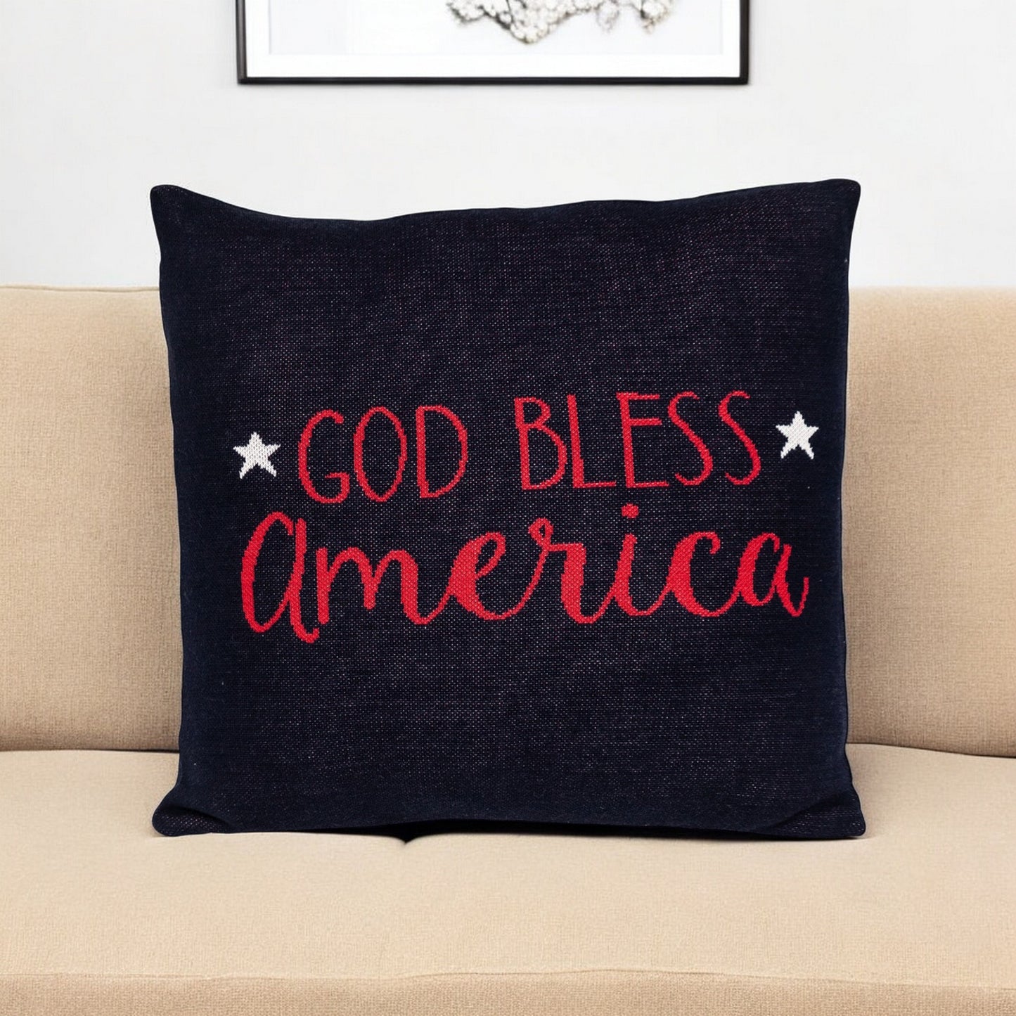 Black pillow with 'God Bless America' text on a beige couch