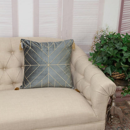 Beige sofa with a decorative pillow featuring geometric patterns, placed in a room with a plant and window blinds.