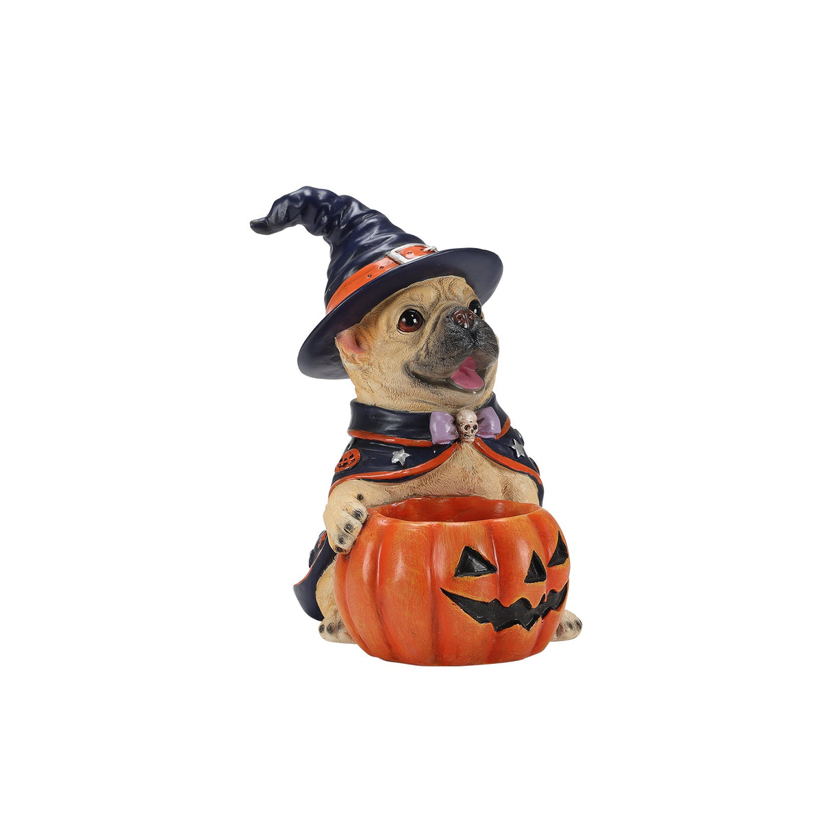 A Halloween-themed figurine of a pug dressed as a witch, wearing a black and orange hat and cape with a purple bow tie, sitting behind an orange jack-o'-lantern bowl. The figurine is photographed on a clean white background.