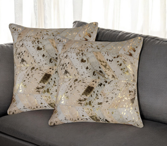 Decorative pillows with a gold and beige pattern on a gray sofa.