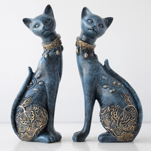 Two blue cat figurines with gold patterns on a white background