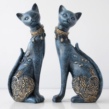 Two blue cat figurines with gold patterns on a white background