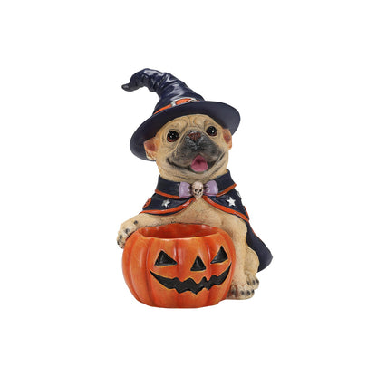 A decorative figurine of a pug dressed as a witch, wearing a black pointed hat and cape with a purple bow tie, sitting behind an orange jack-o'-lantern bowl on a plain white background.