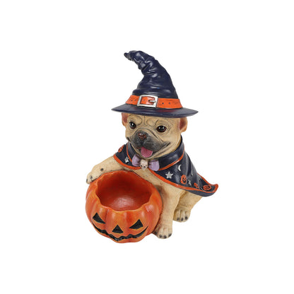 A decorative figurine of a pug dressed as a witch, wearing a dark blue hat and cape with orange trim, holding an orange jack-o'-lantern bucket, on a plain white background.