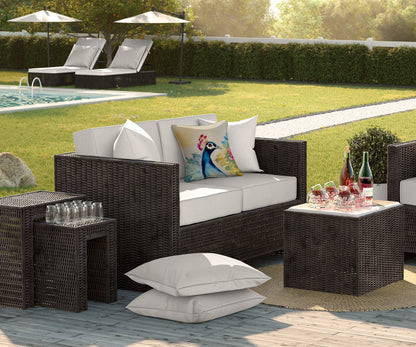 Outdoor patio furniture set with cushions and drinks by a poolside.