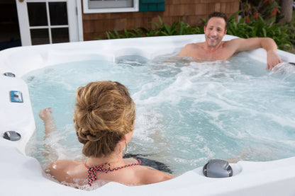 Two people in a hot tub outdoors on a sunny day.