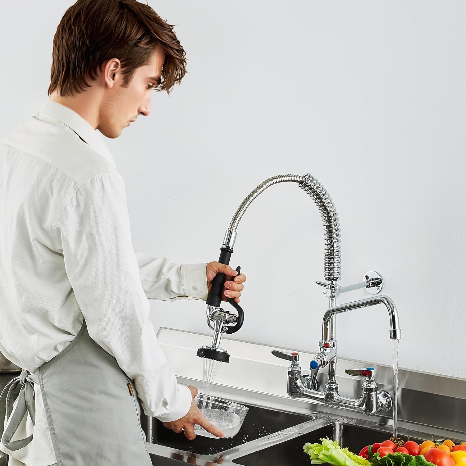Person using a kitchen faucet with a pull-out spray head in a modern kitchen.