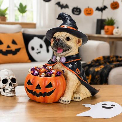 A decorative figurine of a pug dressed as a witch sitting in a pumpkin-shaped bowl filled with wrapped candy, placed on a wooden table in a Halloween-themed living room.