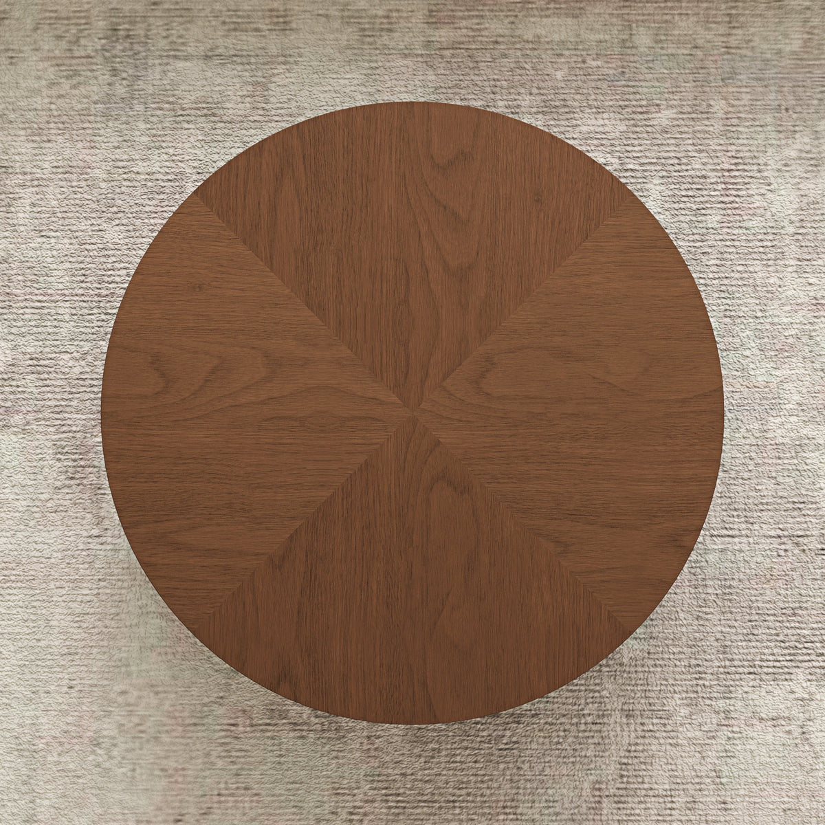 A round wooden coffee table viewed from directly above, featuring a warm medium-brown wood grain finish and a geometric segmented design radiating from the center, set against a textured light beige rug.