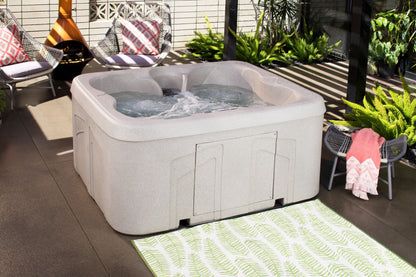 Hot tub on a patio with chairs and plants